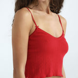 Red spaghetti strap top worn by a model on a white background