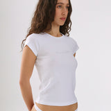 Woman wearing a white t-shirt and white underwear against a plain background