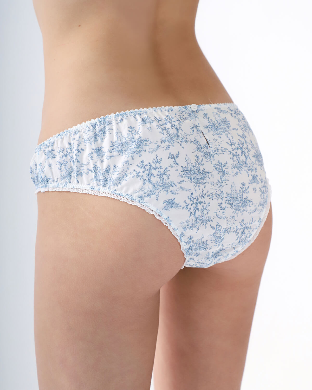 White underwear with blue floral pattern worn by a person on a plain background
