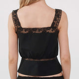 Black lace top worn by a person on a plain background