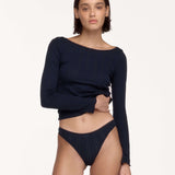 A model wearing a dark navy blue long-sleeve ribbed knit top and matching dark navy underwear, posed against a solid off-white studio background.