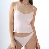 Woman wearing a light pink ribbed camisole and high-waisted brief on a white background