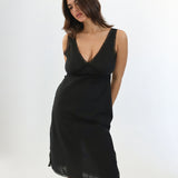 Woman wearing a black slip dress against a white background
