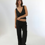 Woman wearing a black sleeveless top and black pants on a white background