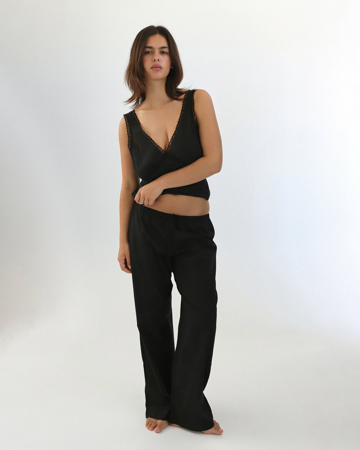 Woman wearing a black sleeveless top and black pants on a white background