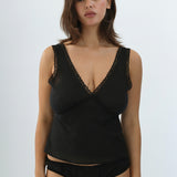 Woman wearing a black lace-trimmed top and high-waisted underwear on a white background