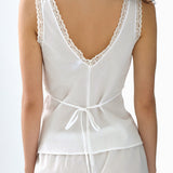White lace-trimmed top worn by a person on a white background