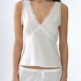 White lace-trimmed top worn by a person on a white background