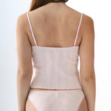 Woman wearing a baby pink top and matching underwear on a white background