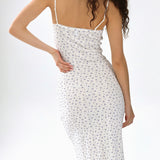 Woman wearing a white dress with a subtle pattern on a plain background