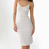 Woman wearing a white slip dress with a floral blue pattern on a white background