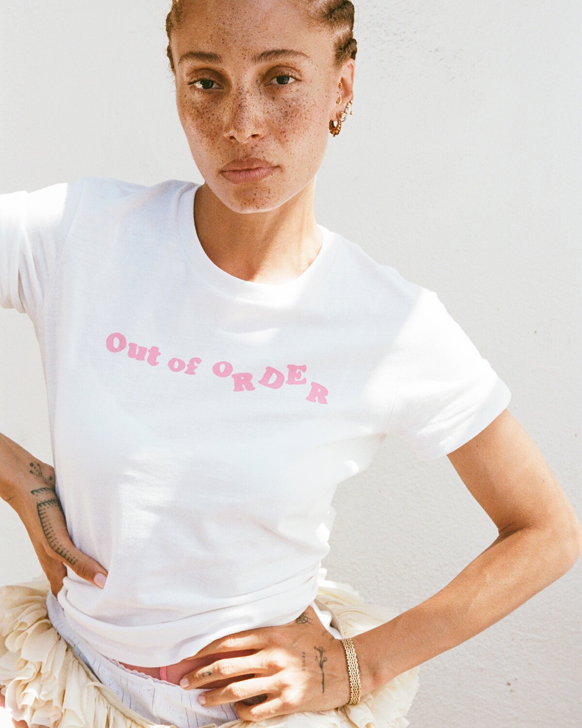 Person wearing a white t-shirt with 'Out of Order' text in pink.