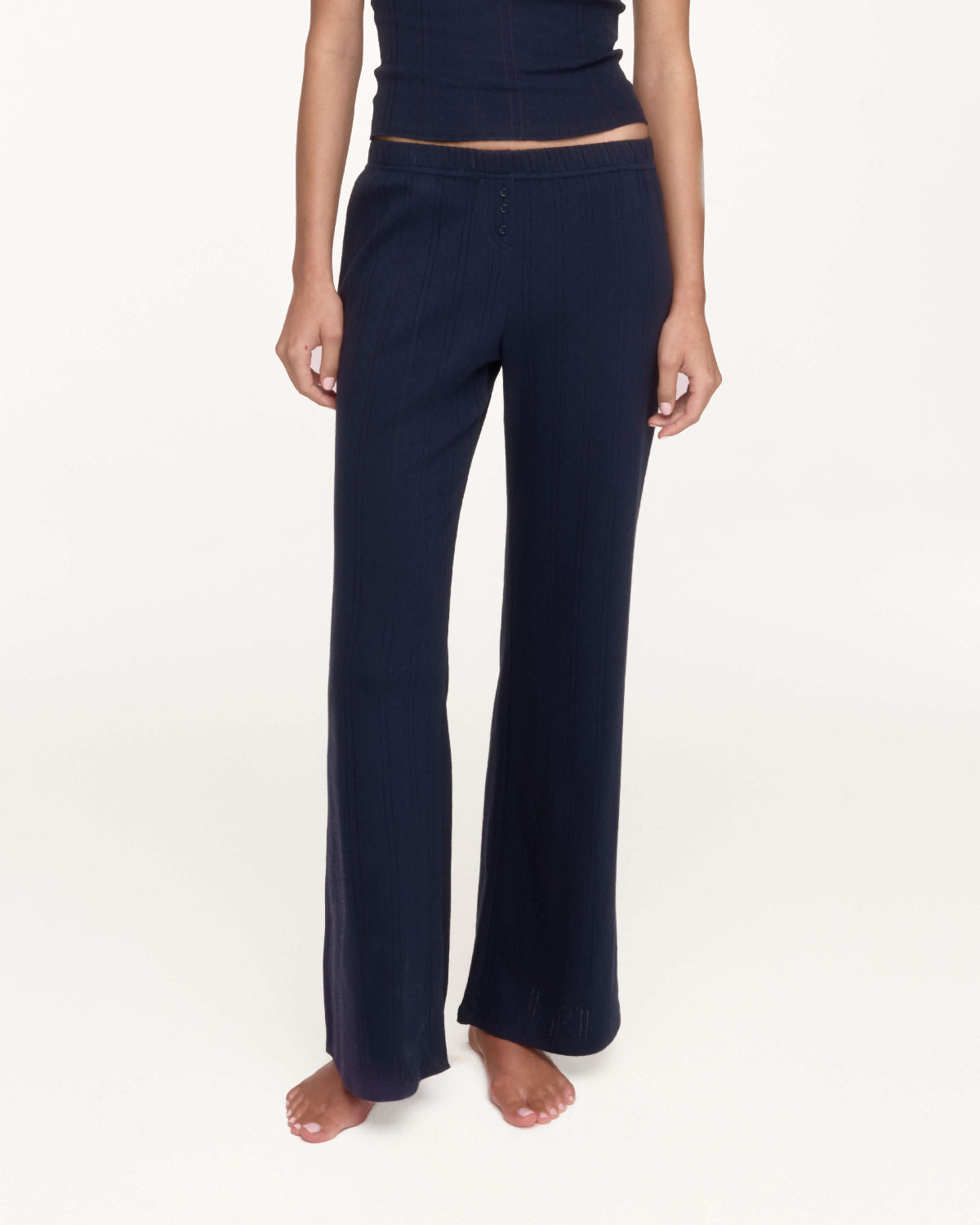 A model wearing a pair of dark navy blue pants, shown from the waist down against a plain white studio background.