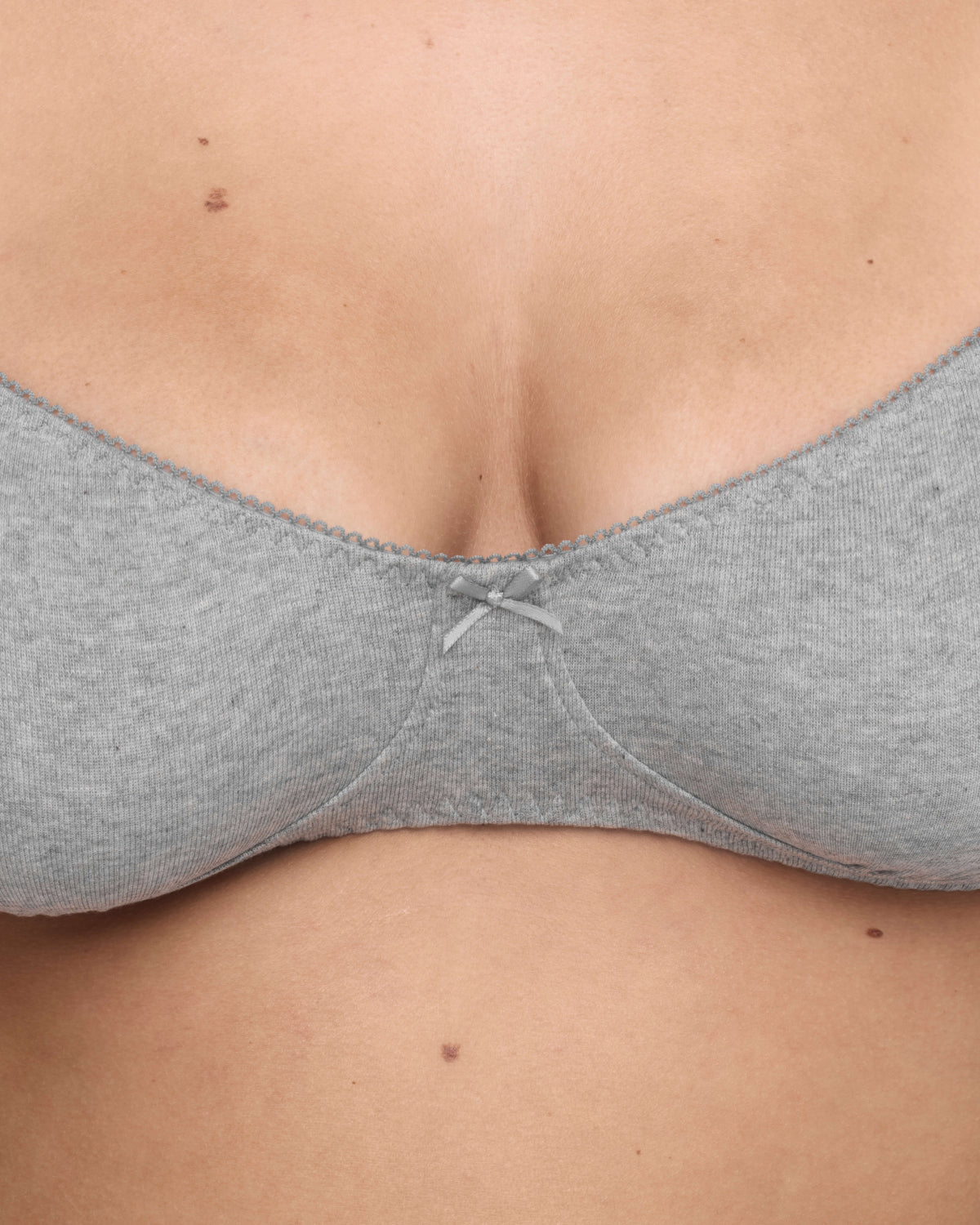 Close-up of a person wearing a light gray bra, showing the center and fabric texture.