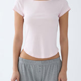 Person wearing a light pink crop top and gray pants on a white background