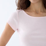 Close-up of a person wearing a light pink top with lace trim on a white background