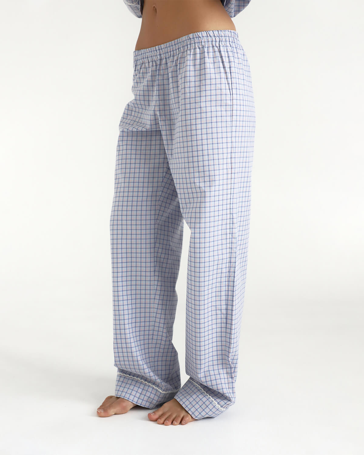 Person wearing blue checkered pajama pants on a white background