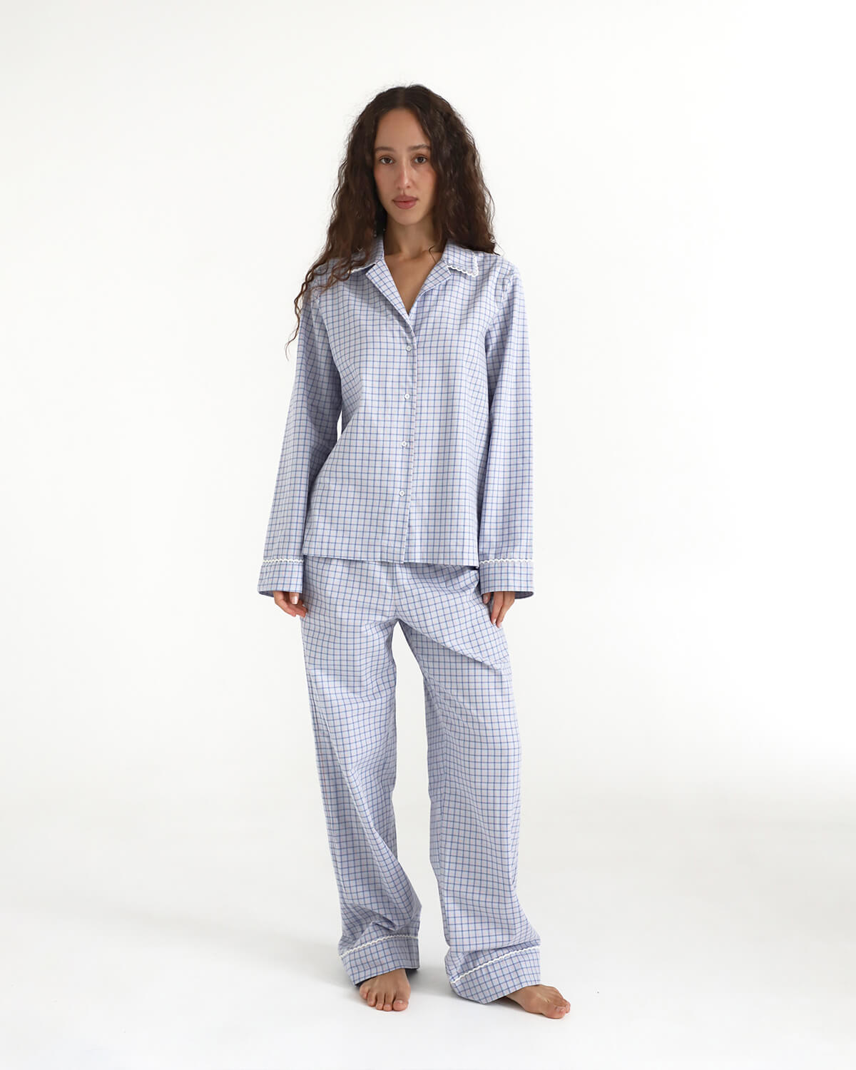 Woman wearing a blue checkered pajama set on a white background