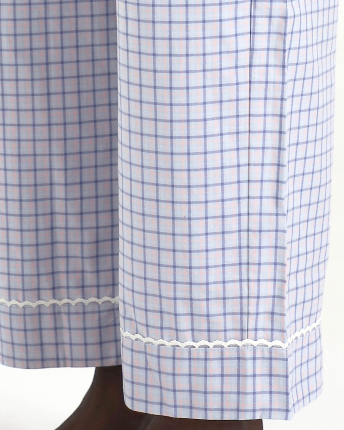 Blue and white checkered curtain with lace trim on a wooden rod.