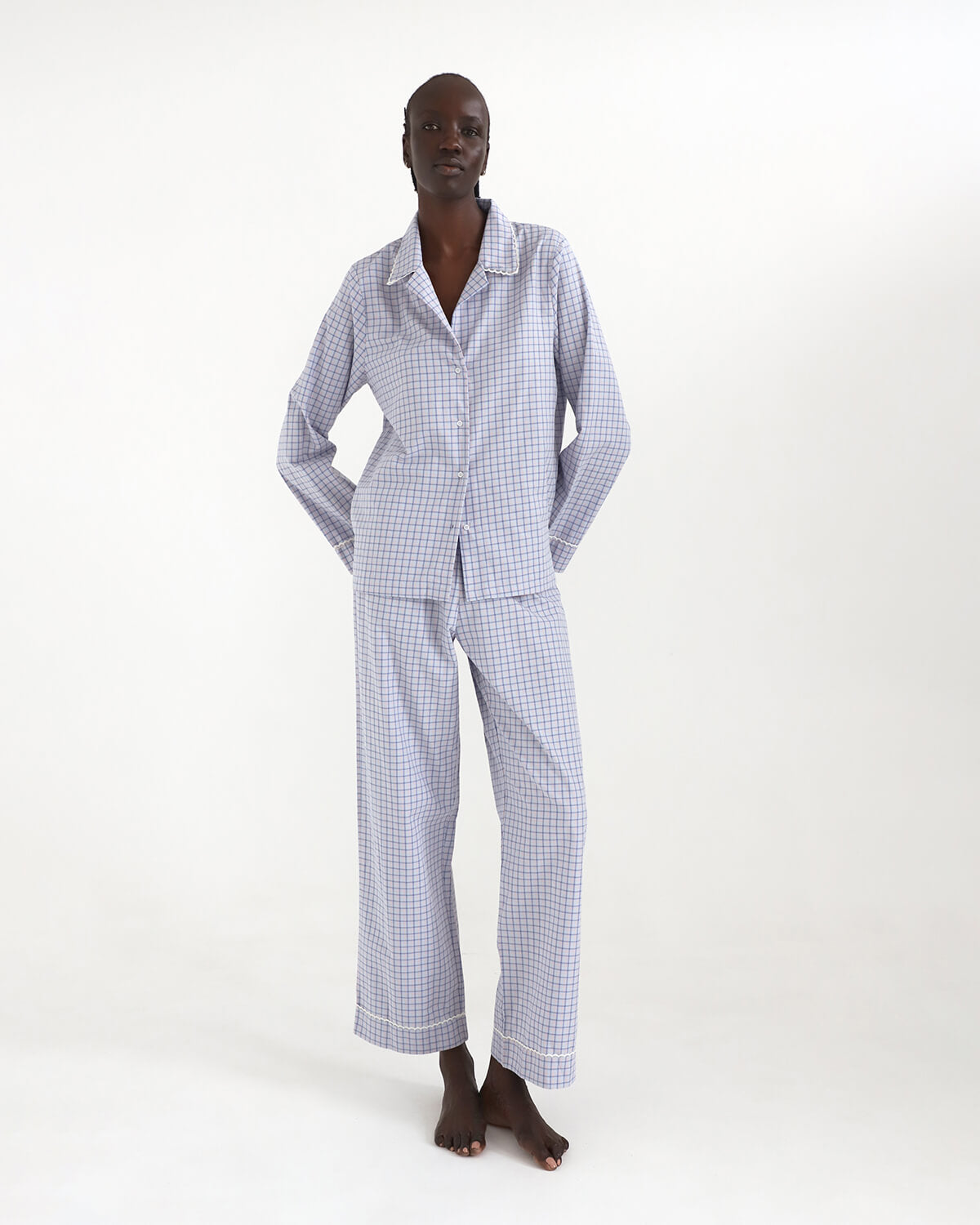 Person wearing a blue checkered pajama set on a white background