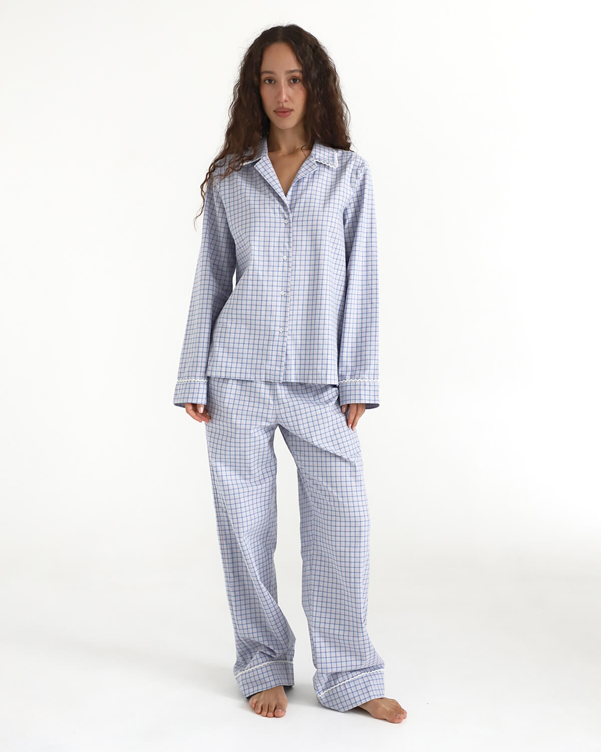 Woman wearing a blue checkered pajama set on a white background