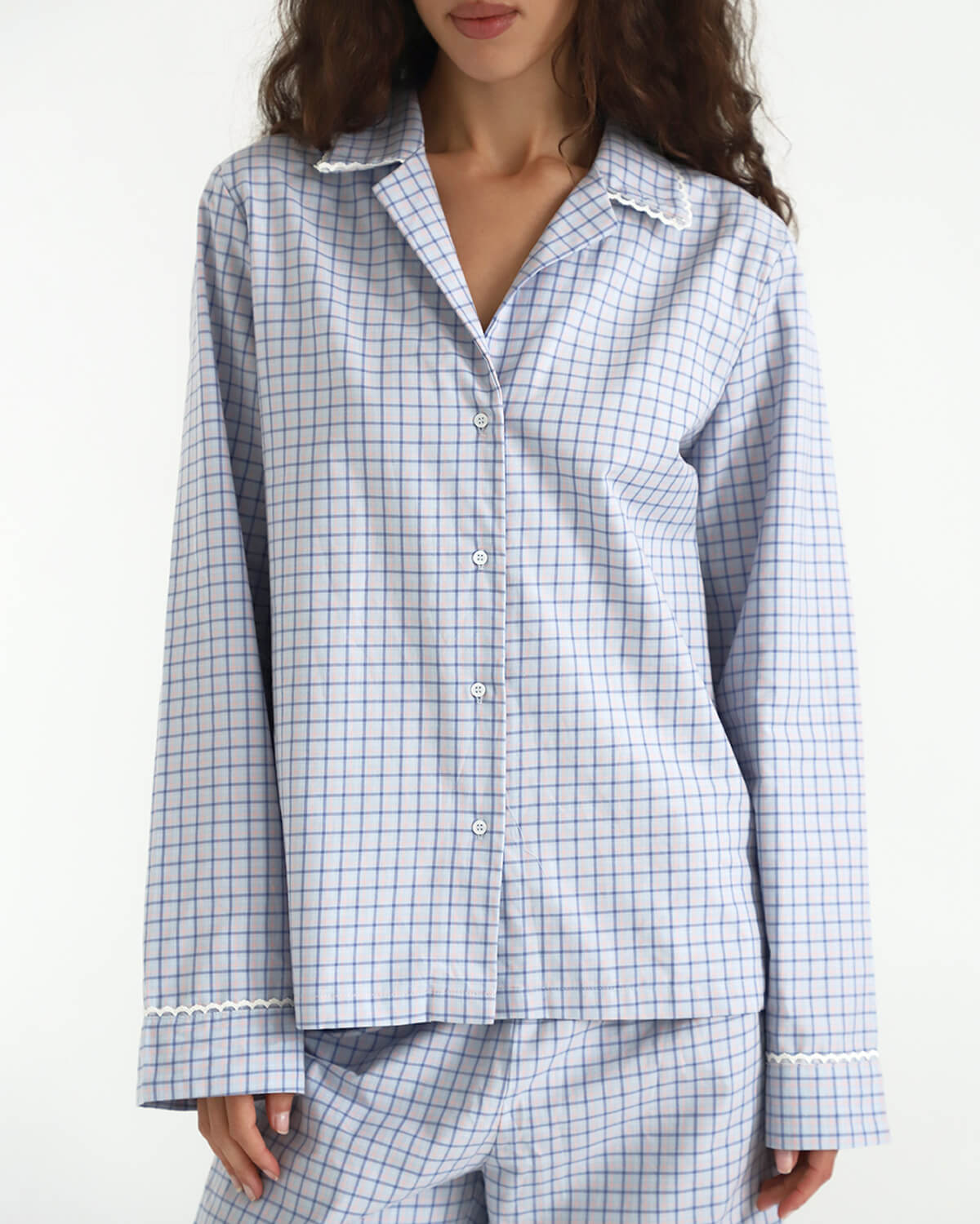 Woman wearing a blue and white checkered pajama set on a white background