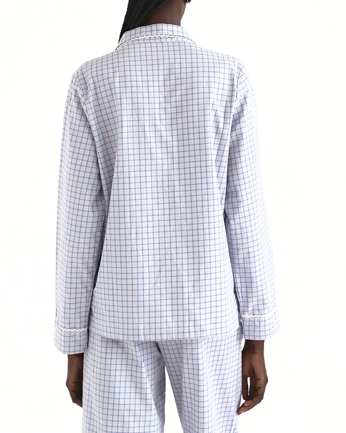 Person wearing a white and blue checkered pajama set on a white background