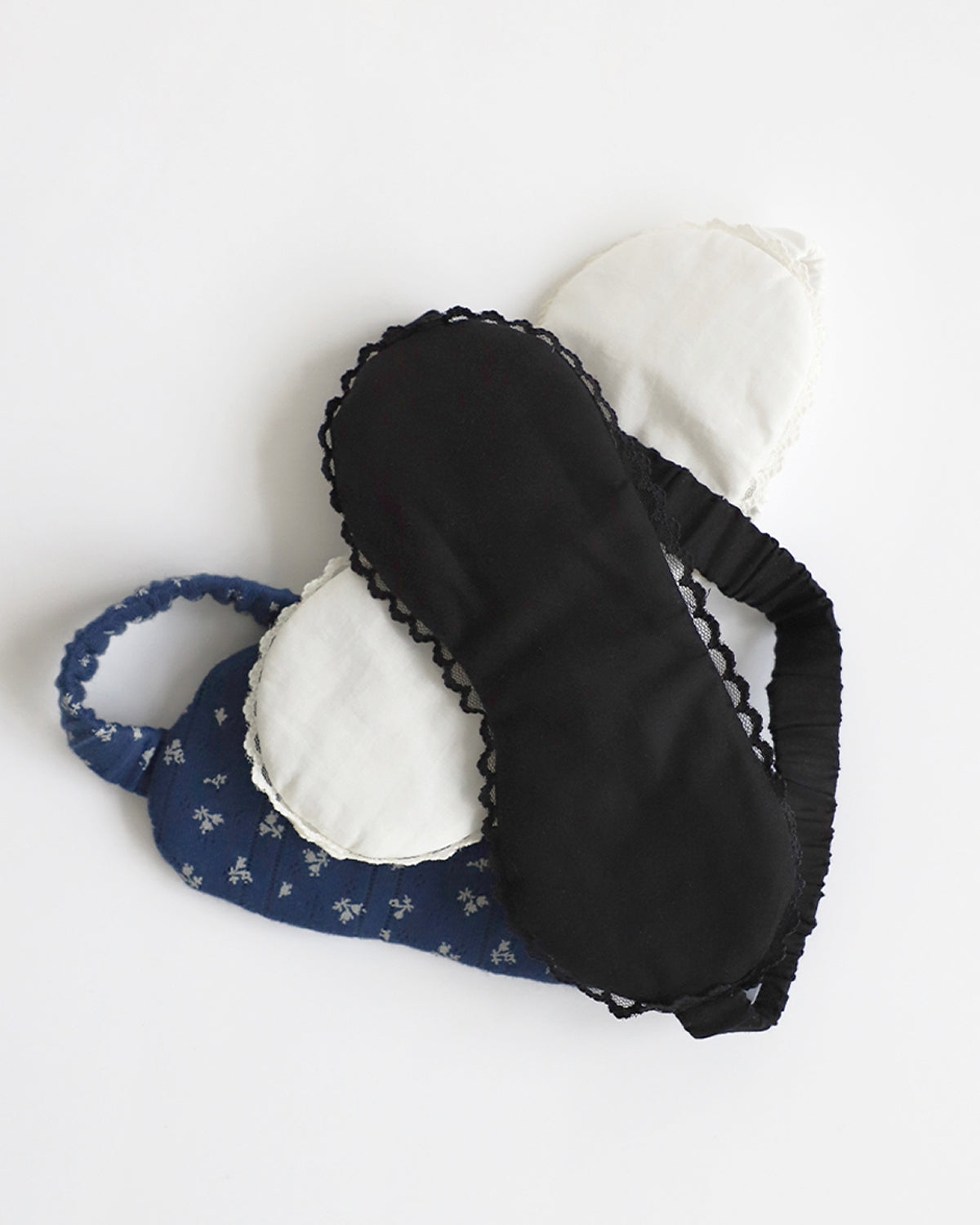 Black eye mask and blue headband with white floral pattern on a white background