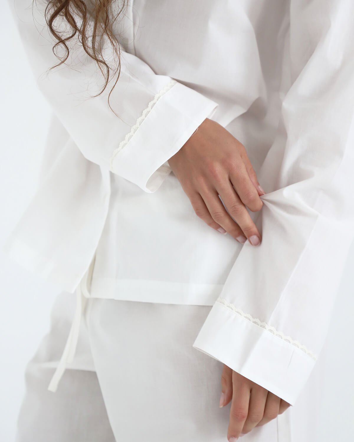 Close-up of a white outfit with bell sleeves on a plain background