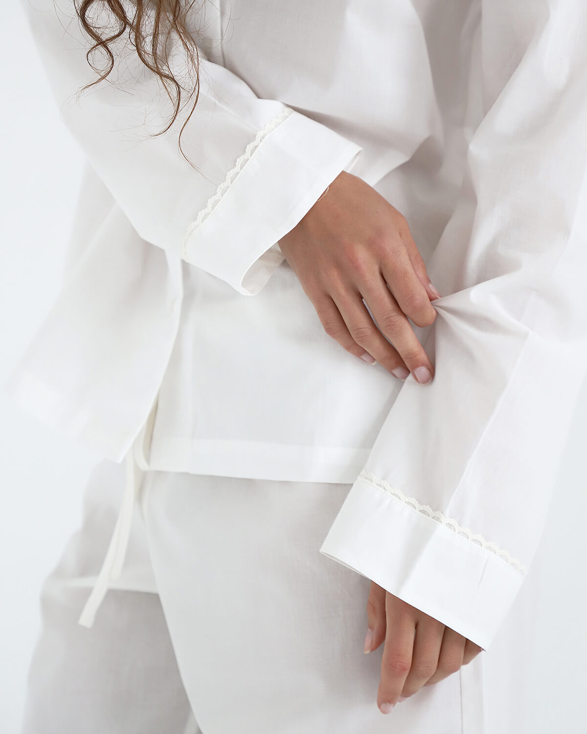 White outfit with cuffed sleeves on a plain background