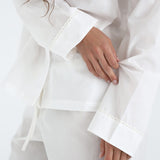 White outfit with cuffed sleeves on a plain background