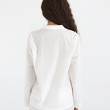 Person wearing a white blazer and pants on a plain background