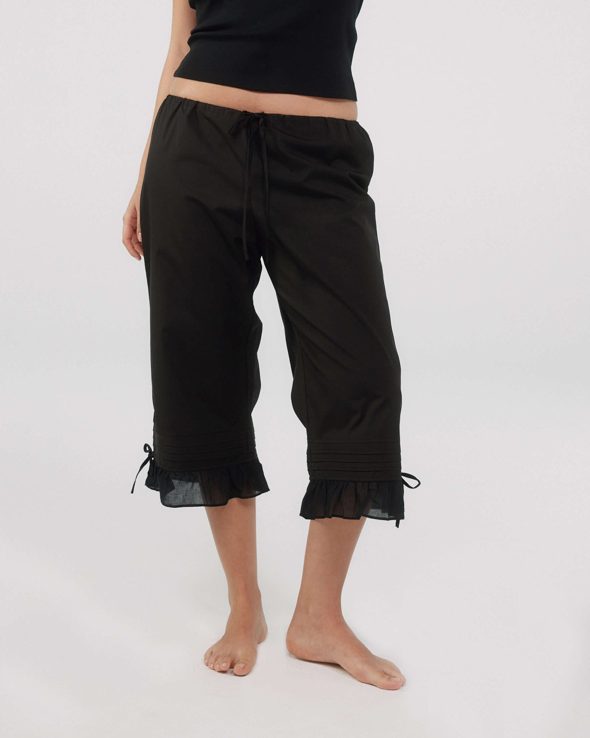 Black capri pants with ruffled hem on a white background