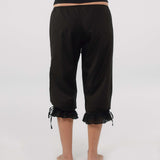 Person wearing black capri pants with ruffled cuffs on a white background