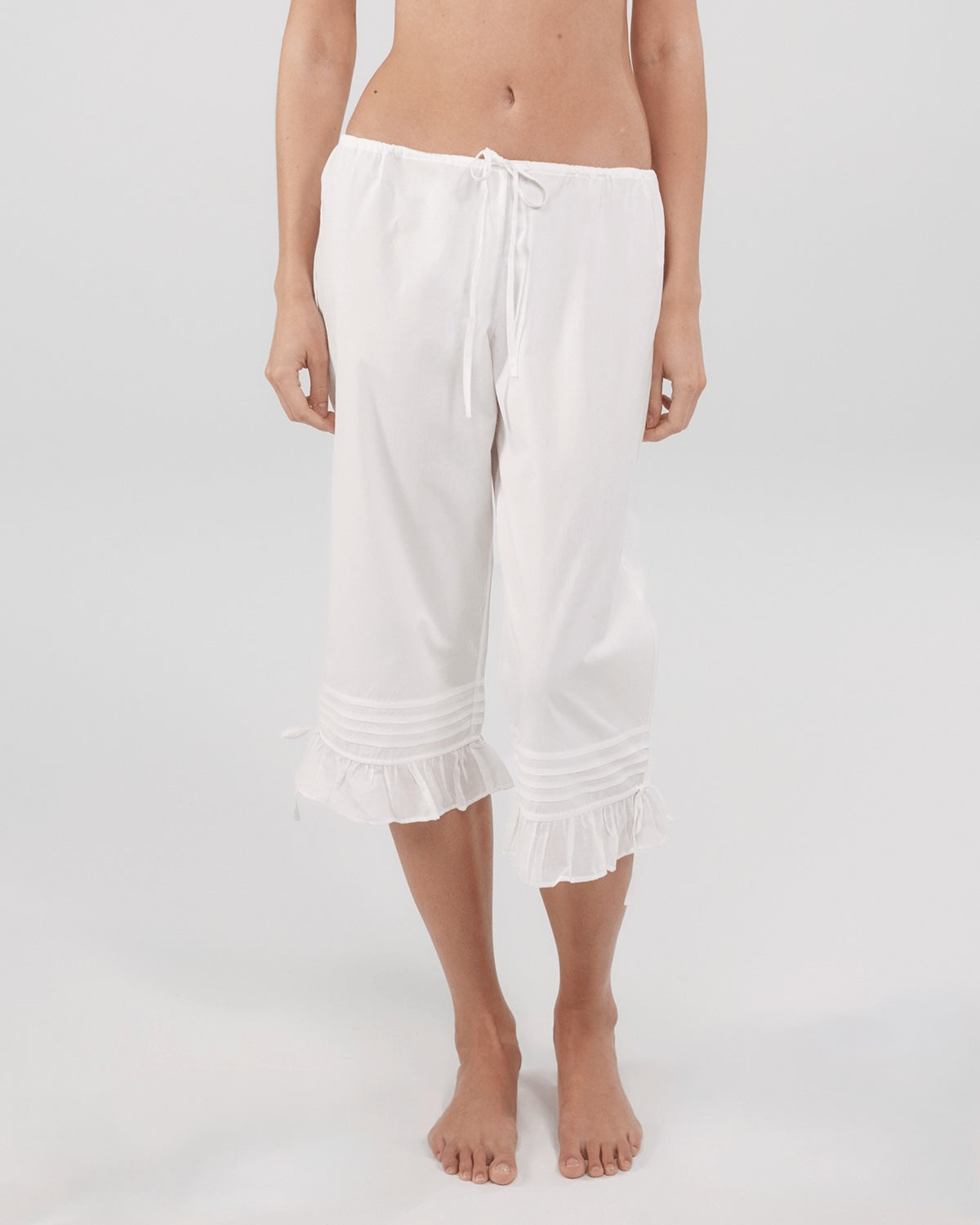 White capri pants worn by a person on a white background