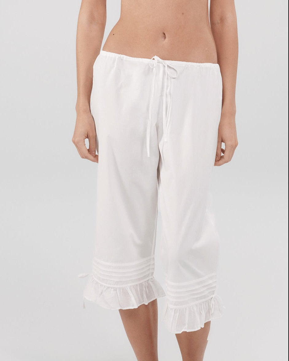 White capri pants worn by a person on a white background
