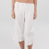 White capri pants worn by a person on a white background