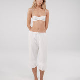 Woman wearing a white bra and pants on a plain background
