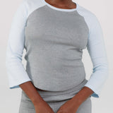 Person wearing a gray and white long-sleeve shirt with a plain background