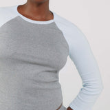 Person wearing a gray and light blue long-sleeve shirt on a plain background