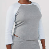 Person wearing a gray and white long-sleeve top with matching shorts on a plain background