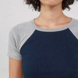 Person wearing a navy blue and gray baseball shirt against a plain background