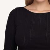 Close-up of a woman wearing a black long-sleeve top against a plain light background.