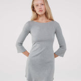 Woman wearing a gray long-sleeve dress against a white background
