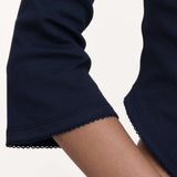 Close-up of a navy blue sleeve with a scalloped hem, worn on a model's arm against a plain light background.