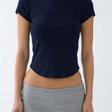 A woman wearing a navy blue short-sleeve knit top with scalloped edges and gray heather shorts, shown from the neck down against a plain light gray background.