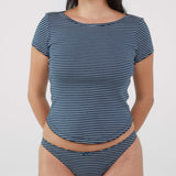 A woman wearing a navy blue and white striped top and matching thong against a plain light gray background.