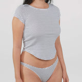 A woman wearing a short-sleeve crop top and matching thong with thin horizontal navy and white stripes, photographed against a light gray studio background.