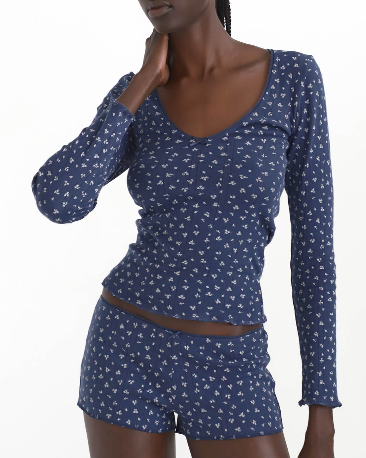 Woman wearing a blue patterned long-sleeve top and shorts set on a white background