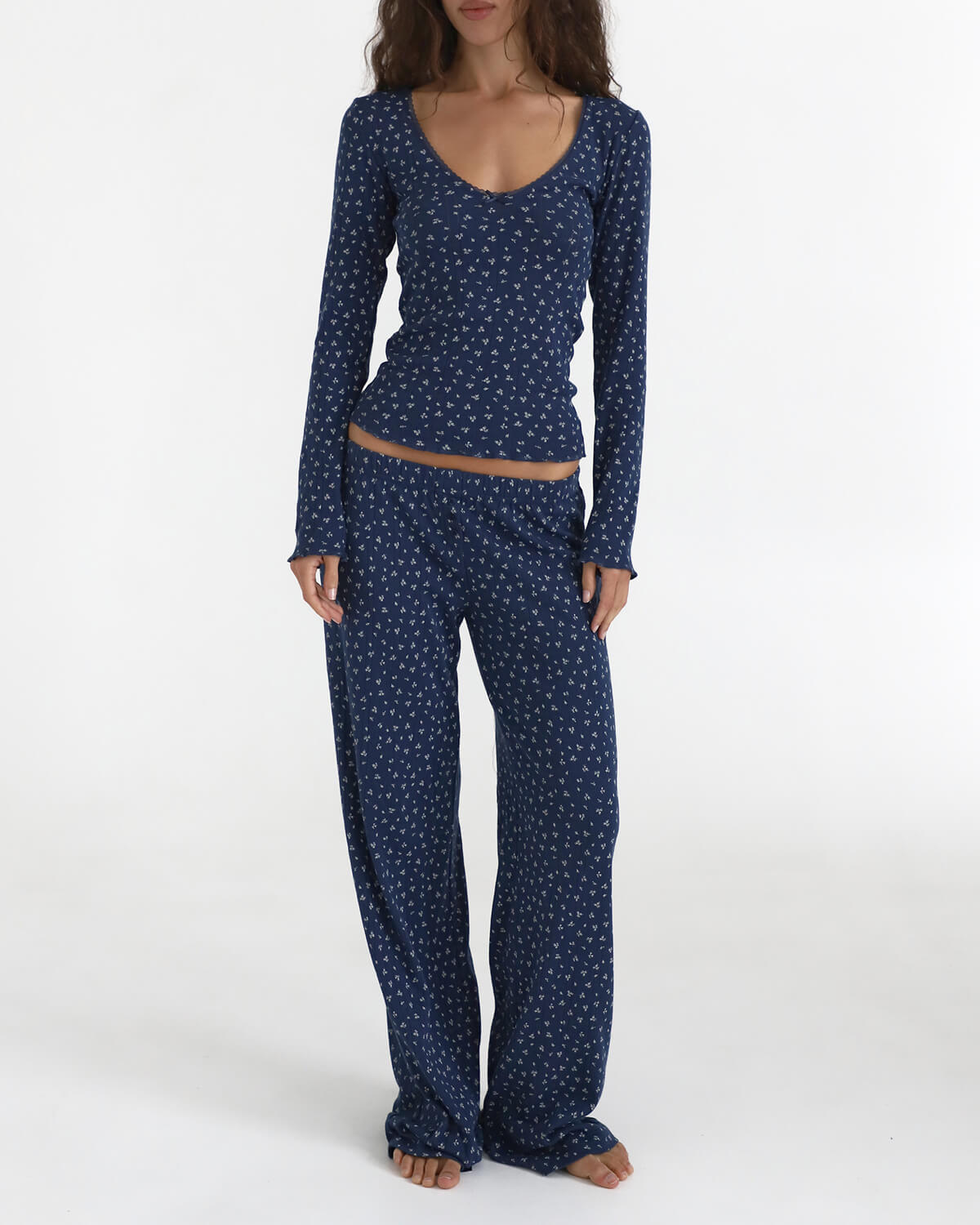 Woman wearing a navy blue pajama set with white floral pattern on a white background